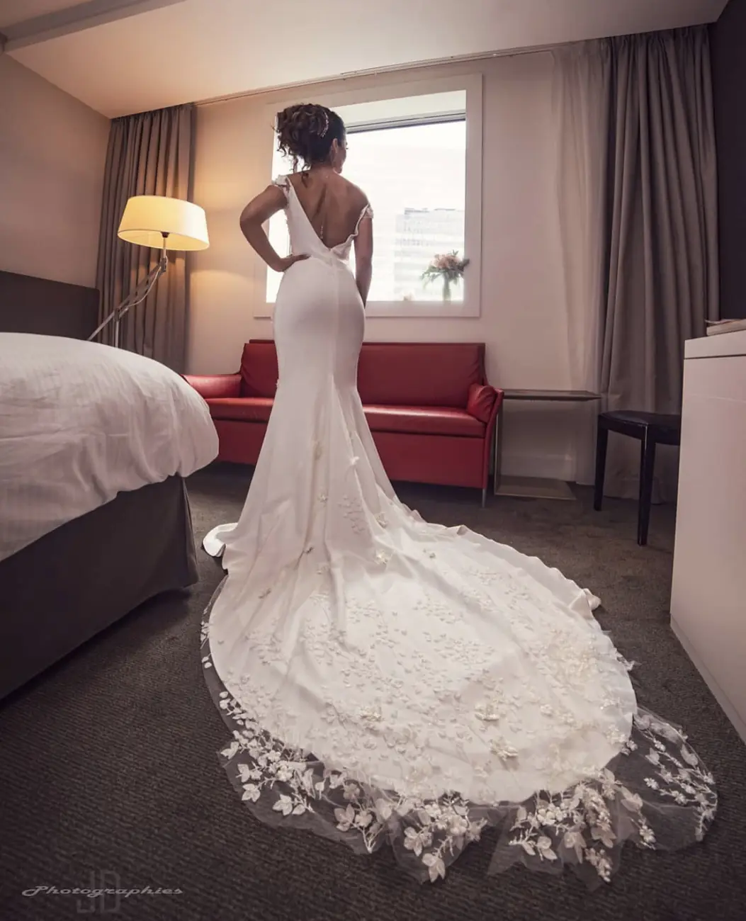 Mariée en robe à traîne dans une chambre d'hôtel